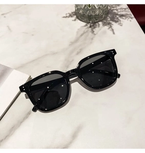 Detail of black square frame sunglasses with silver metal dots on marble surface
