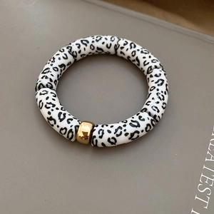 Detail of leopard print cylinder beads bracelet with a polished gold metal bead accent