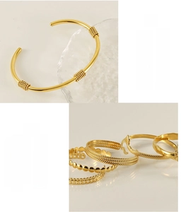 Detail of gold stainless steel twisted bangle and stacked jewelry with waterproof finish