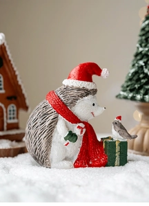 Miniature resin hedgehog figurine with red Santa hat and bird on a festive gift box