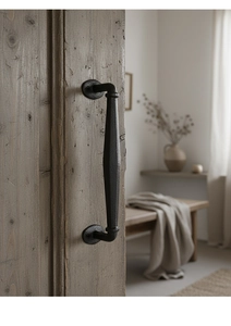 Detail of vintage black cast iron door handle with hammered texture on solid wood