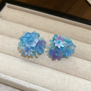 Detailed macro view of handmade blue and purple beaded flower earrings on beige velvet