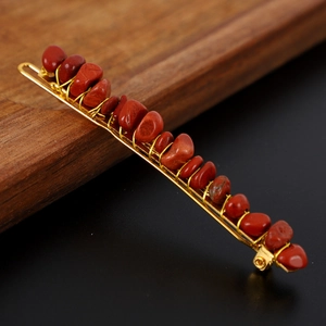 Detailed close-up of handmade red natural stone hair clip with gold wire wrapping