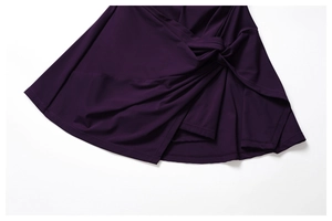 Detail of dark purple tennis dress featuring a side knot design and pleated hemline
