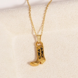 Détail d'un pendentif botte de cow-boy doré avec motifs en émail noir sur tissu beige
