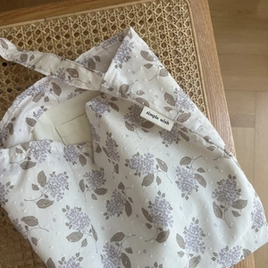Close-up of floral jacquard cotton fabric and woven label on small lavender shoulder bag