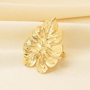 Close-up of golden monstera leaf ring on white silk, showing detailed hollow texture