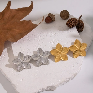 Textured flower stud earrings in gold and silver finish on natural stone background