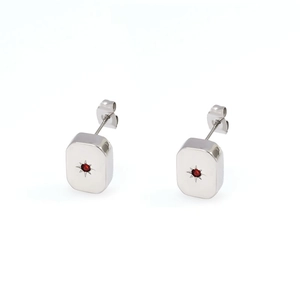 Macro shot of silver rectangular stud earrings with red center stone and starburst carving
