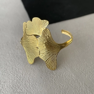 Macro view of gold ginkgo leaf open bracelet with fine vertical textured metal finish