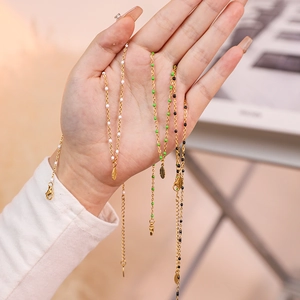 Detail view of feather pendant necklaces with colorful beads on delicate gold chains