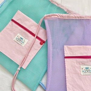 Detail of lightweight mesh backpack with contrast colors, drawstring, and zipper pouch
