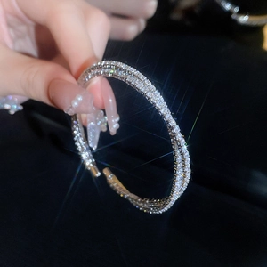 Close-up of sparkling double-layer criss-cross silver bangle with inlaid cubic zirconia