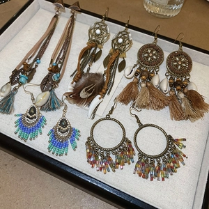 Detailed view of Bohemian tassel earrings with beads, feathers and shells on a tray