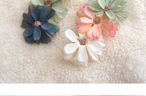 Detailed view of handmade fabric daisy hair clips in soft morandi colors on white texture