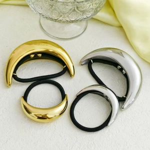 Close-up of gold and silver curved metal hair rings with black elastic bands
