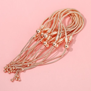 Close-up of rose gold snake bone chain bracelets with adjustable bead on pink background