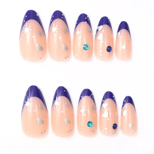 Detail of almond-shaped press-on nails with blue French tips, silver stars, and blue rhinestones