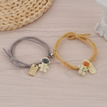 Dettaglio di bracciali magnetici per coppia astronauta con corda intrecciata su legno