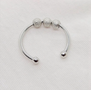 Detailansicht eines silbernen drehbaren Angst-Rings mit drei mattierten beweglichen Perlen