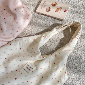Detail of floral tote bag fabric with sozakka beaute label on soft beige rug