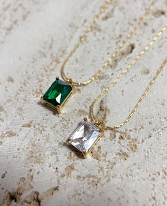 Detail of emerald green and clear square zircon pendants on gold titanium steel chains