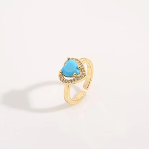 Detail showing gold heart ring with blue gemstone inlay and sparkling crystals
