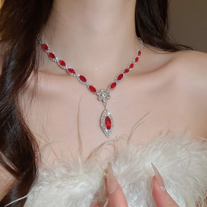 Detail of silver necklace featuring red marquise-cut gems and leaf-shaped pendant