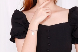 Close-up of adjustable silver bracelet with square pearl pendant on a model wrist