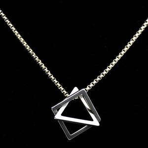 Silver geometric interlocking triangles pendant with box chain on a dark background