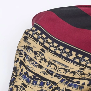 Close-up of red diagonal stripes and blue ethnic paisley pattern on premium woven fabric