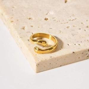 Golden stainless steel hug ring with hands design on natural stone background