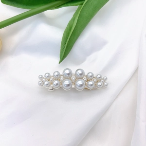 Elegant side hair clip with double-layer pearls and gold base on white silk fabric