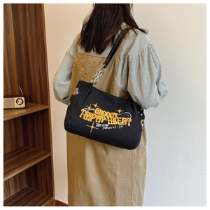 Black canvas tote bag featuring vibrant letter embroidery and metal chain shoulder strap