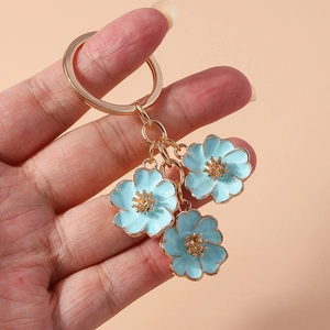 Detailed close-up of light blue enamel peach blossom pendants on a gold keychain
