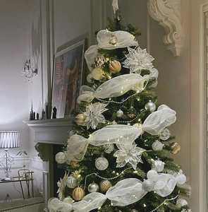 Close-up of a decorated Christmas tree with white mesh ribbon, gold ornaments and snowflakes