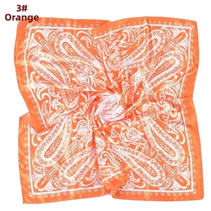 Close-up of orange paisley print on a satin square scarf with a glossy finish