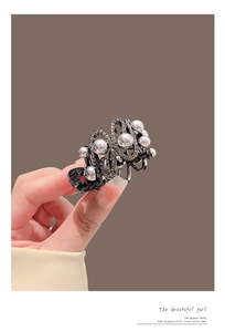 Détail d'une pince à cheveux en métal avec perles blanches et strass brillants