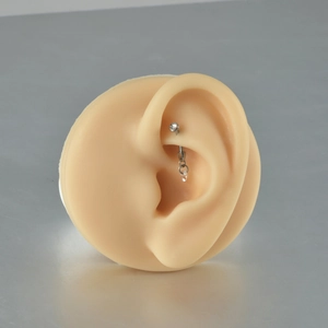 Detailed view of silver titanium piercing with opal and cubic zirconia on an ear model