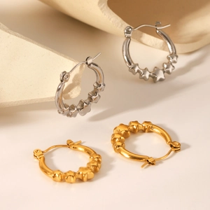 Polished stainless steel star hoop earrings in gold and silver finish on a neutral base