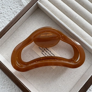 Detail of amber jelly hair claw clip with cutout design on a wooden display