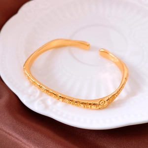 Détail d'un jonc ouvert plaqué or 24 carats avec gaufrage de caractères rétro