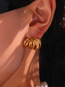 Macro shot of gold-plated twisted spiral C-shape earring on a model earlobe