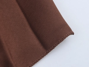 Detailed view of dark brown twill fabric with precise edge stitching on the dress