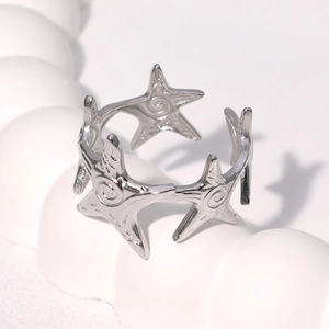 Silver starfish adjustable open ring made of polished stainless steel on white pedestal