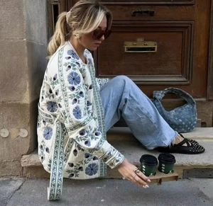 Vue détaillée de la veste matelassée blanche avec broderie florale bleue et lien noué