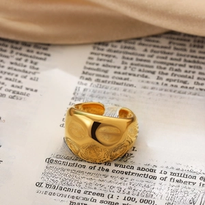 Macro shot of gold water-drop knot ring with wavy textured surface on book pages