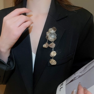 Close-up of a luxury gold flower brooch with rhinestones and tassels on a black blazer