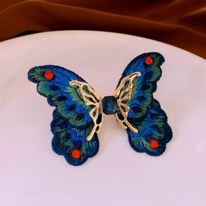 Macro shot of embroidered butterfly ring with blue silk thread and central blue gemstone