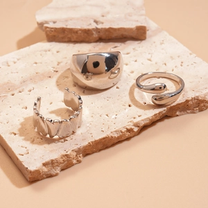 Detailed view of silver rings set with irregular geometric designs on beige stone props